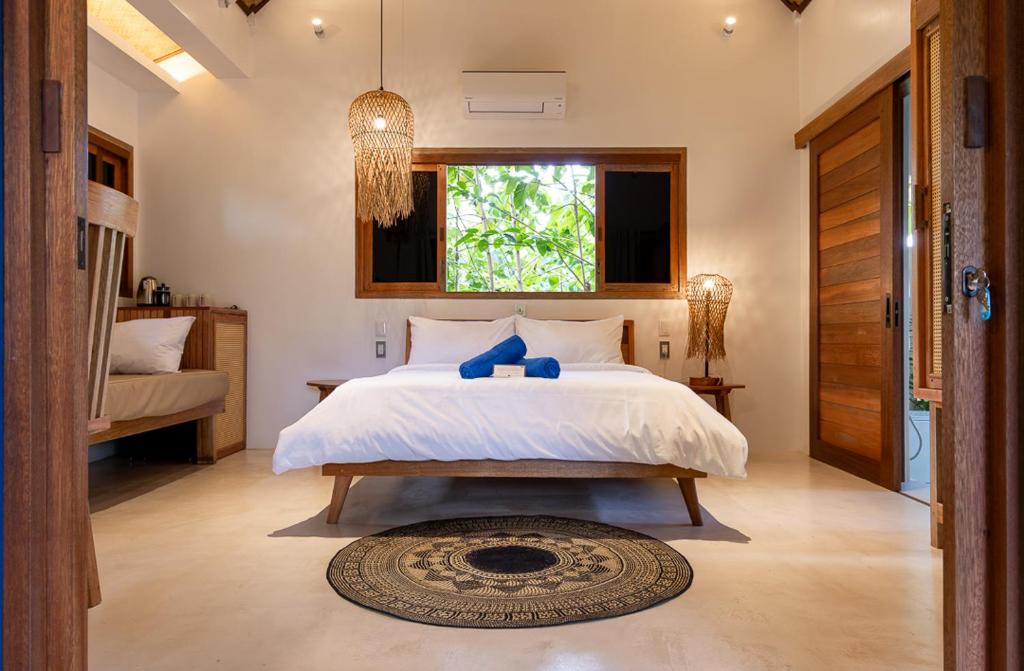 a bedroom with a large white bed and a window at Confluence Siargao in General Luna