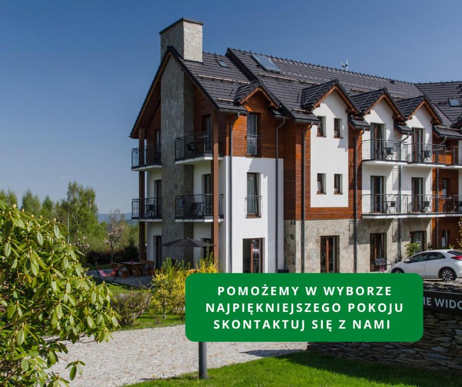 a building with a sign in front of it at Karkonoskie Widoki - Jacuzzi z widokiem na Śnieżkę - pyszne śniadania i parking w cenie - pokoje z balkonami in Karpacz