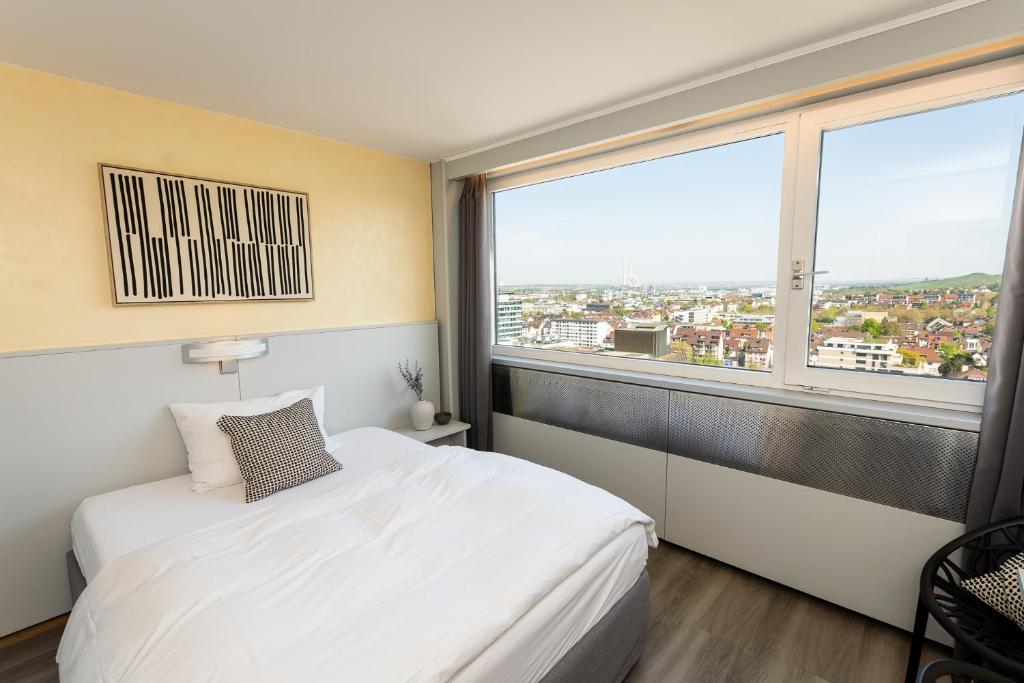 a bedroom with a white bed and a large window at City Hotel Heilbronn in Heilbronn