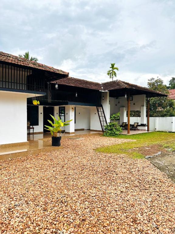 a house with a gravel driveway in front of it at Cherys Bunglow Homestay- Rooms in Thiruvalla