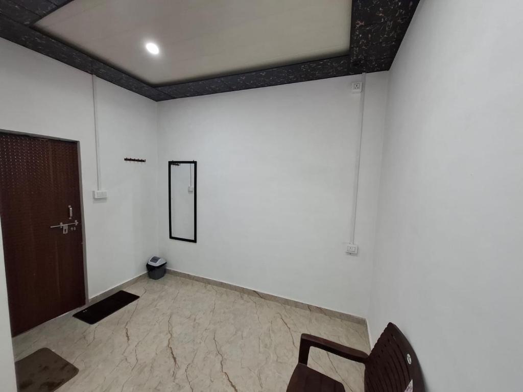 a room with white walls and a door and a chair at Shivansh Homestay in Mathura