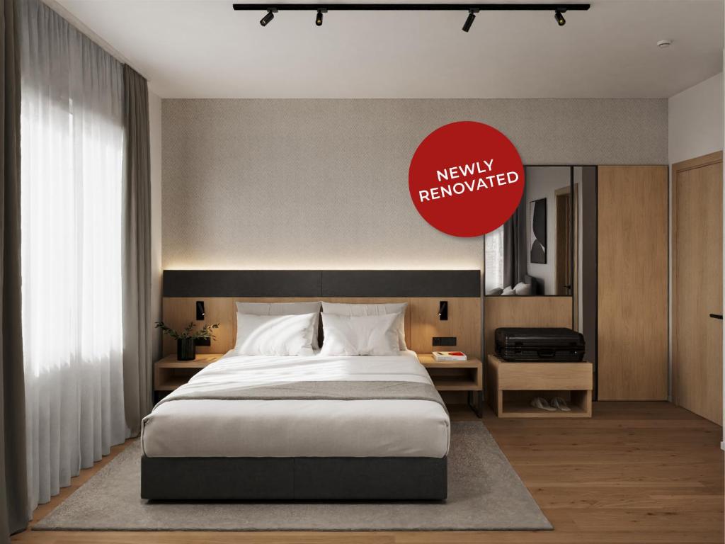 a bedroom with a large bed and a red sign at Tailormade Hotel AL GIARDINETTO Biasca in Biasca