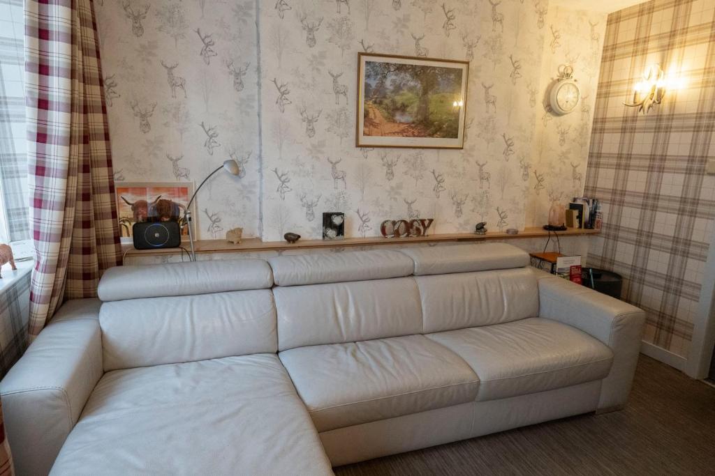 a living room with a white couch in a room at 1BR Charming Cottage in Central Moffat in Moffat