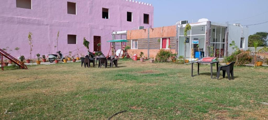 a group of tables in a yard next to a pink building at Hotel krishna manu place in Orchha