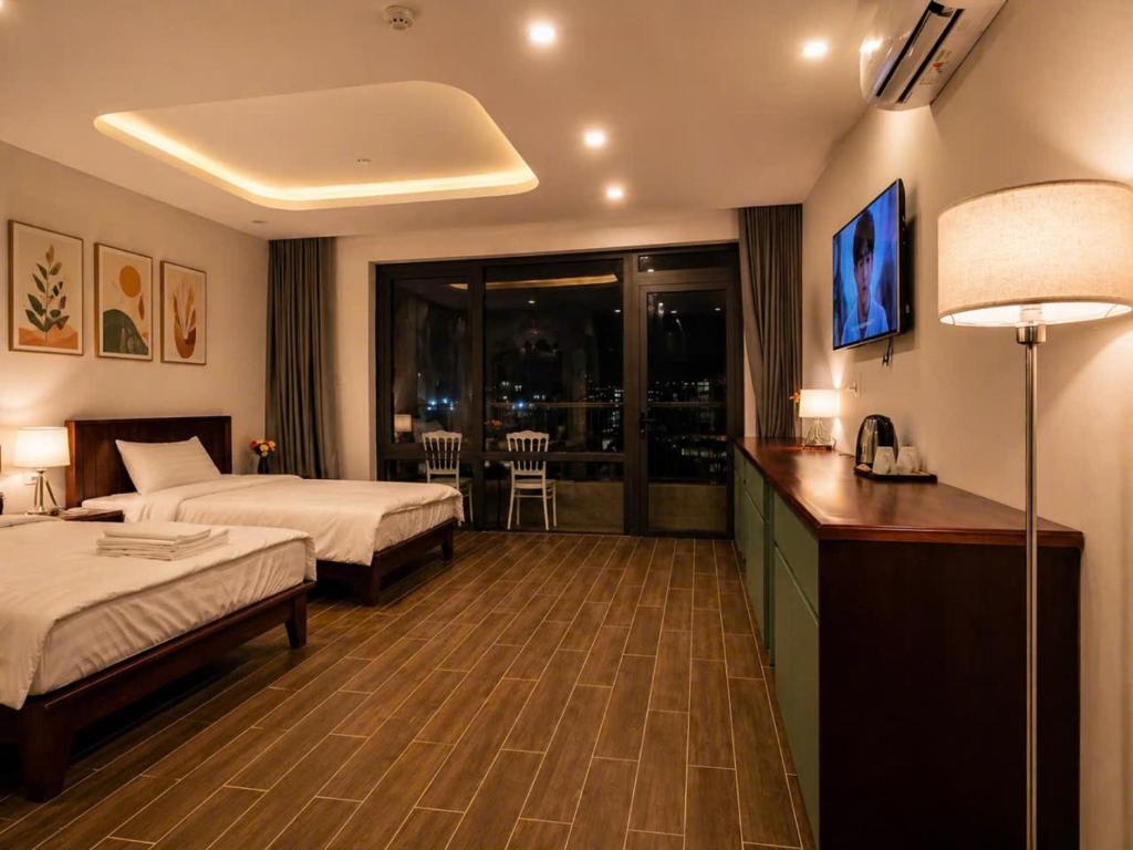 a hotel room with two beds and a desk at Bareka Hotel in Phú Quốc