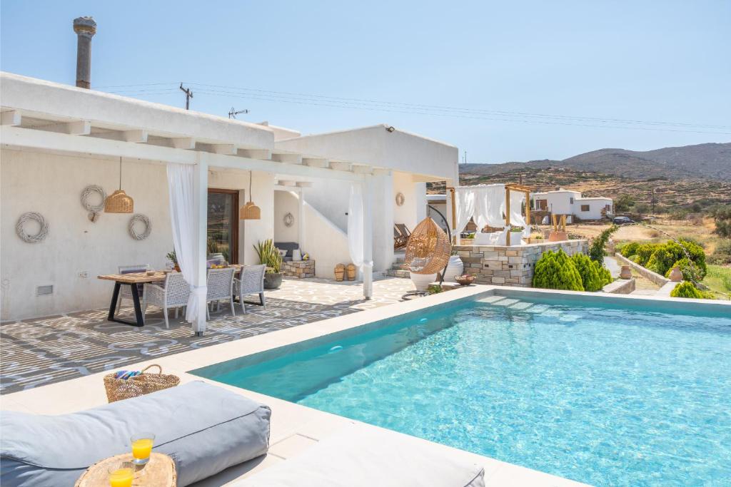 a villa with a swimming pool in front of a house at Revery Villa & House in Ios Chora