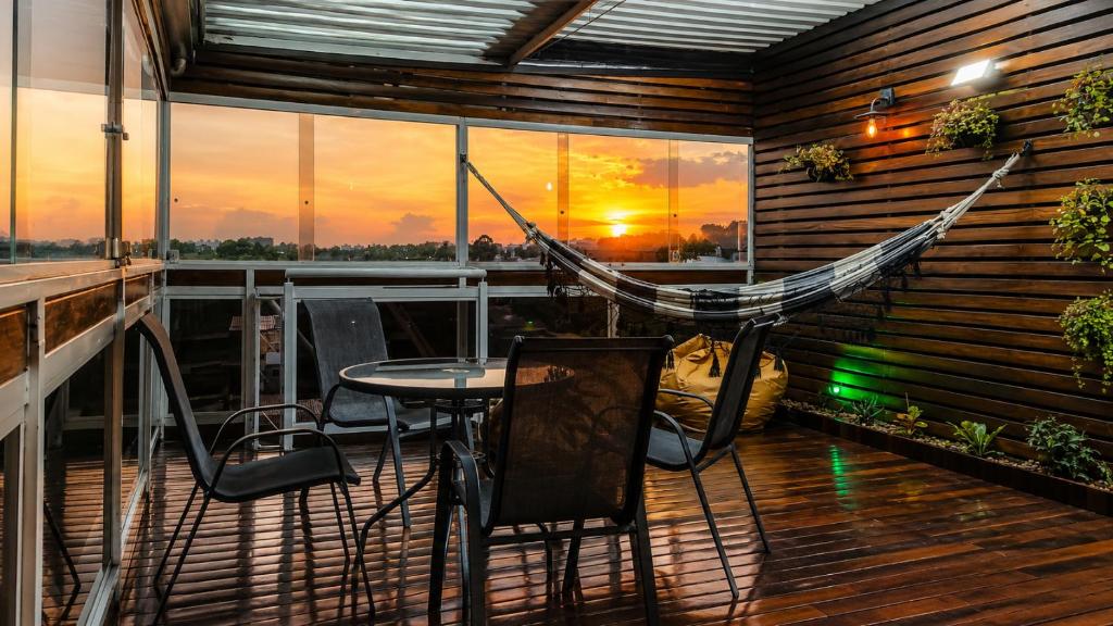 a hammock on a balcony with a table and chairs at Lá Casa do Manguinha in Guarulhos