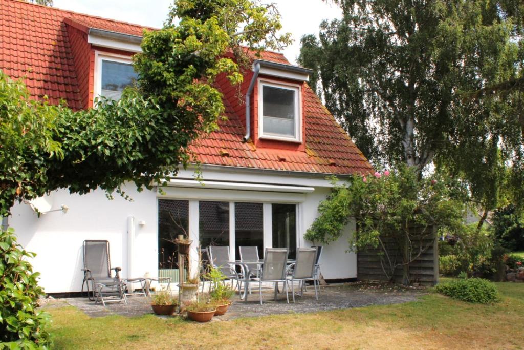 a house with chairs and tables in a yard at Ferienhaus Lütt Matten in Wustrow