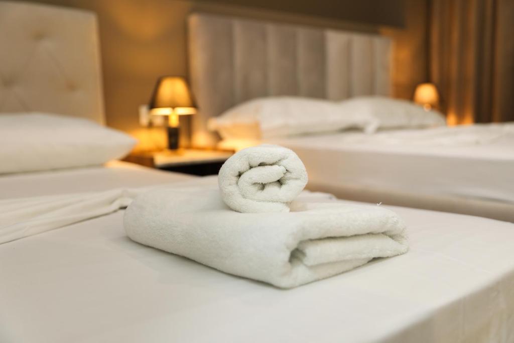 a pile of towels on a bed in a hotel room at Hotel HER in Vlorë