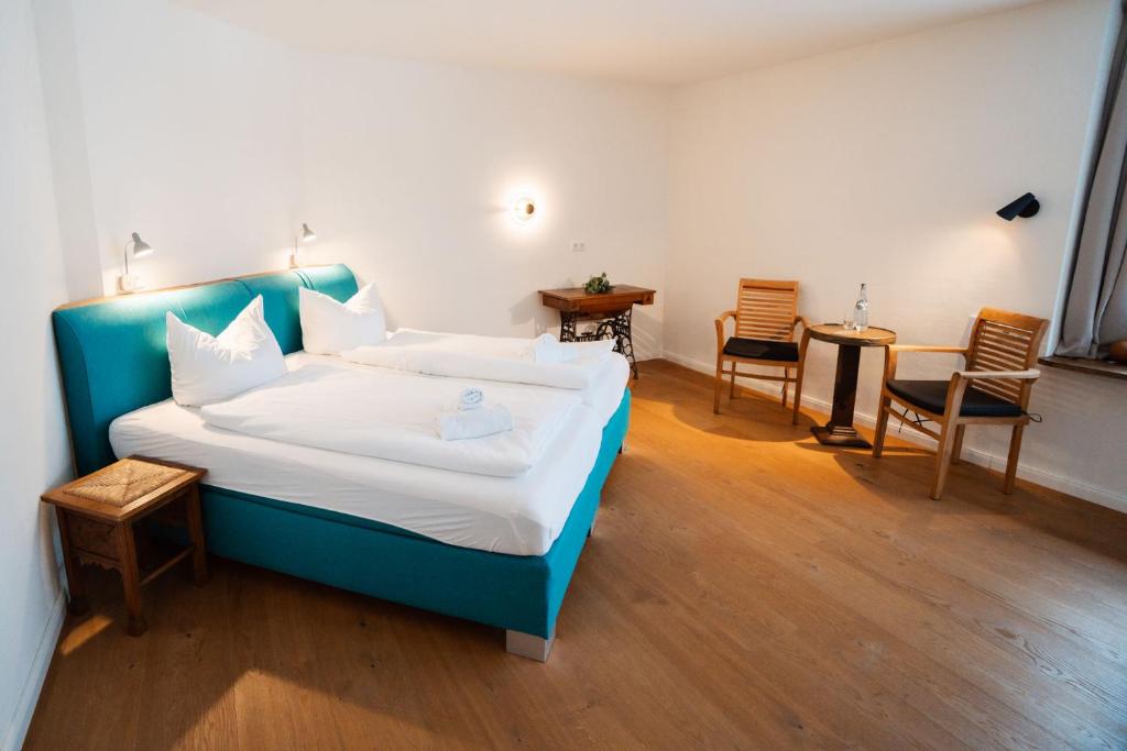 a bedroom with a blue bed with two chairs and a table at Hotel Lethehof in Wardenburg
