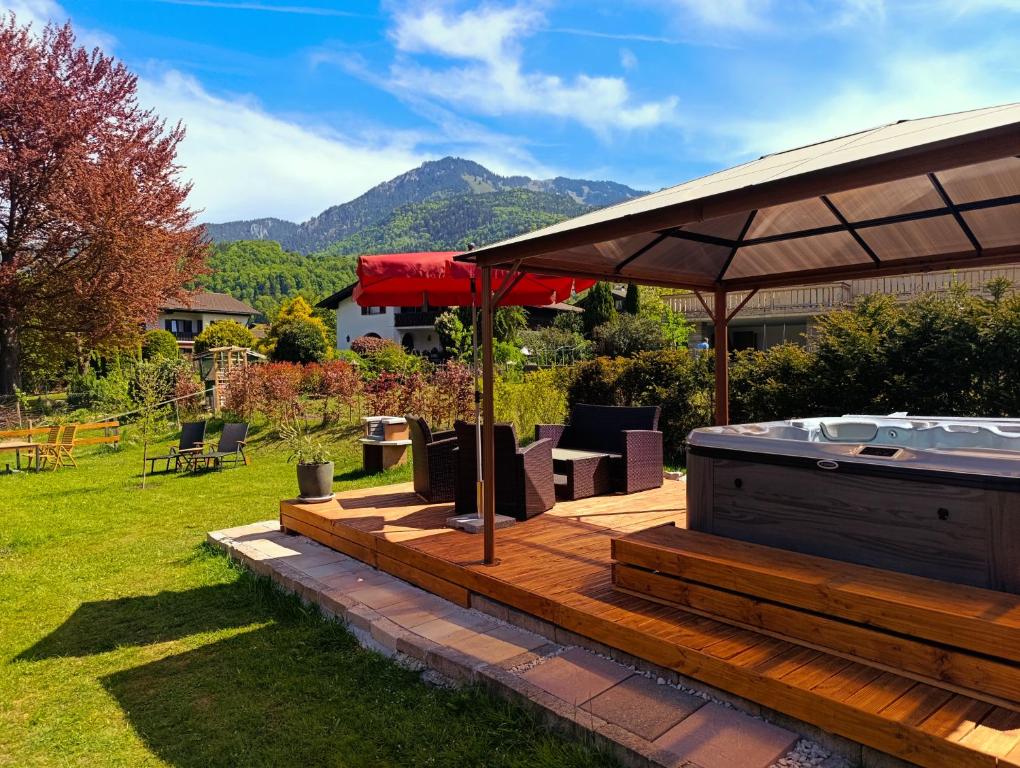 a deck with a hot tub and an umbrella at Chiemgauferienwohnungen - Wanderlust und Alpenrose in Unterwössen