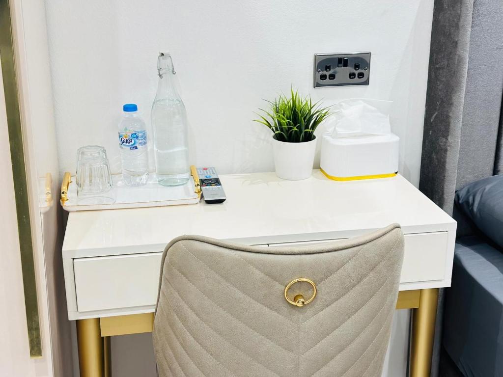 een wit bureau met een stoel en flessen erop bij Tower Studio in Londen