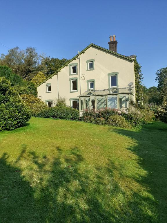 a large white house sitting on top of a lush green field at Forest How Guest House in Eskdale