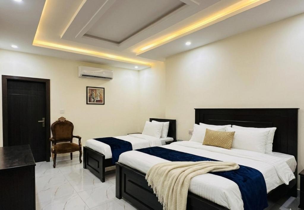 a hotel room with two beds and a chair at Mak Palace Hotel in Sialkot