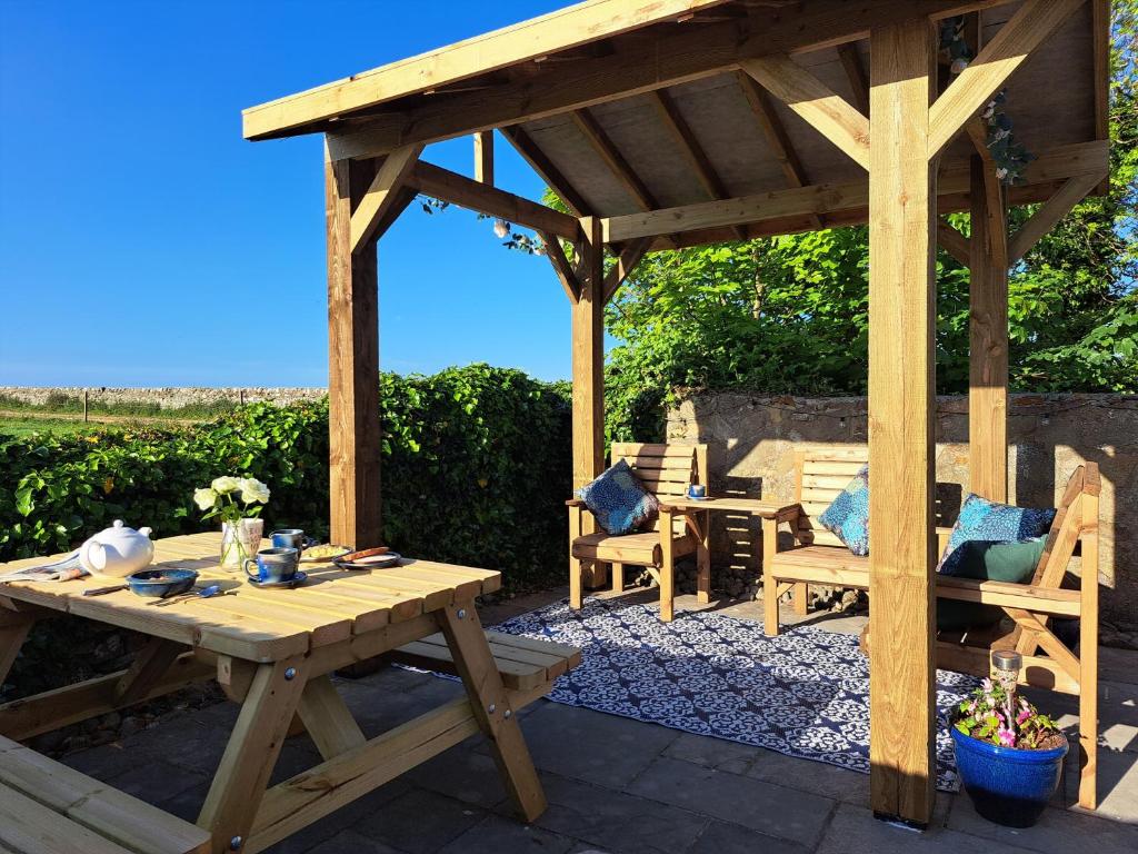 a wooden pergola with a wooden table and chairs at Mulberry Cottage in Whithorn