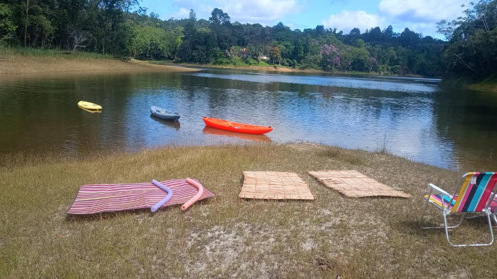 two chairs and umbrellas on the shore of a lake at Chácara Desejo do Coração 1 in Juquitiba
