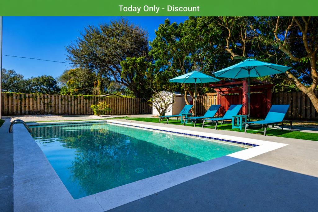 a swimming pool with two blue chairs and umbrellas at Relax & Fun Hollywood Private Pool | Arcade Game in Hollywood