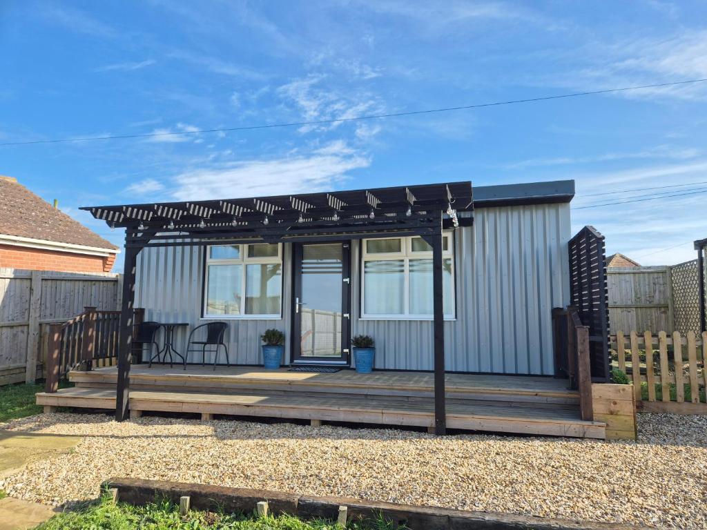 a small house with a deck with a black awning at Zoila's Rest - A self-contained studio in Spalding