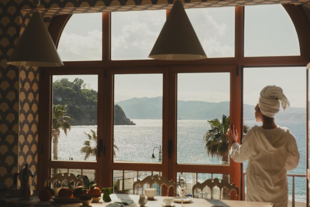 a woman looking out of a window at the water at La balza di Scilla in Scilla