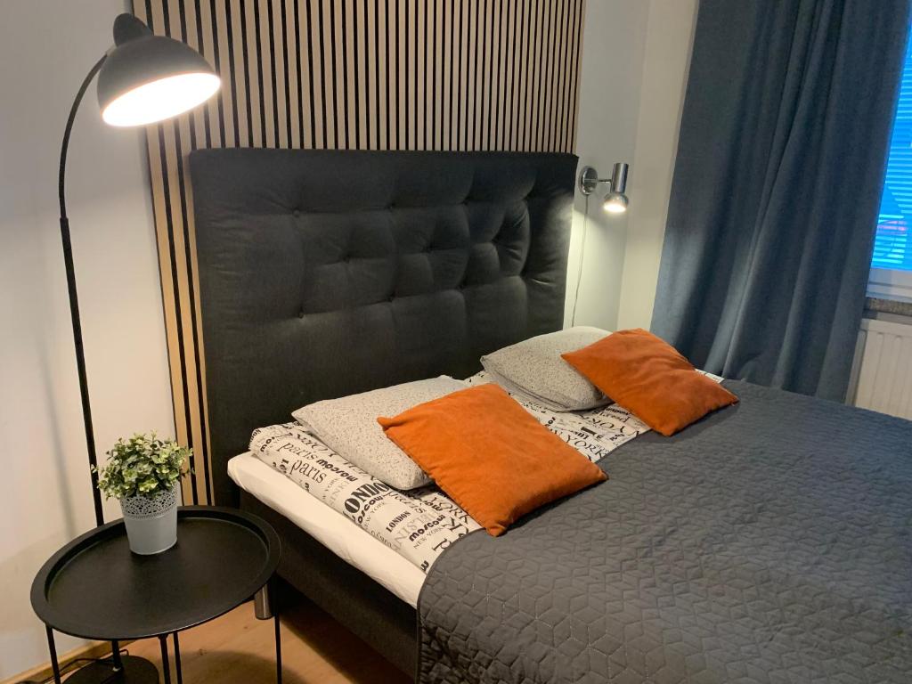 a bedroom with a bed with orange pillows and a lamp at StarHomes Oulu, double in Oulu