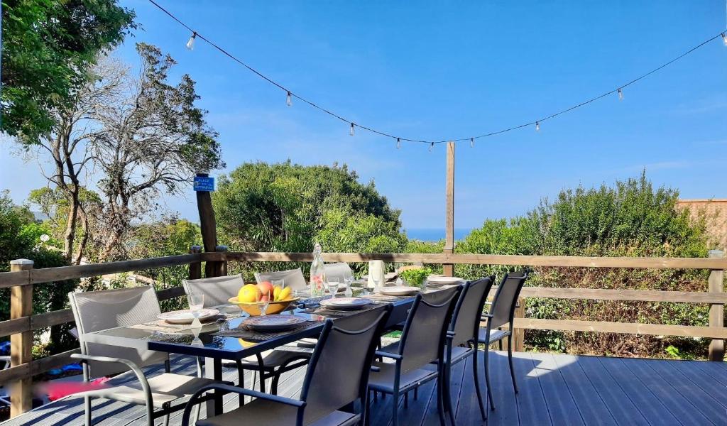 a dining table and chairs on a deck at Piscine & Vue Mer, Maison Familiale Corse, accès cascade in Santa-Maria-Poggio