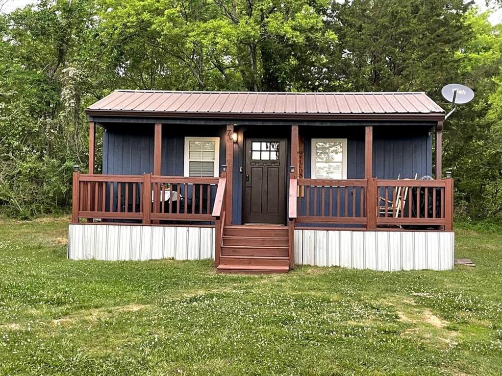 a small cabin with a porch and a door at Cozy Tiny Home Cabin in Eva, TN in Eva