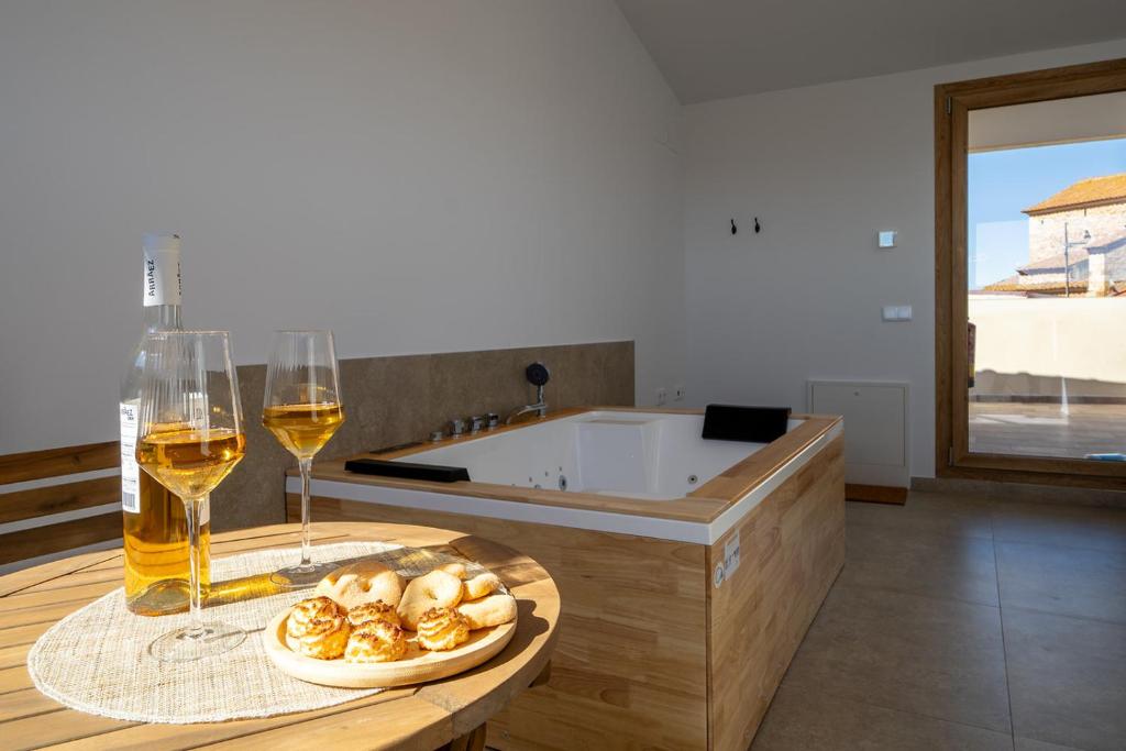 a table with a plate of food and two glasses of wine at OSTALEA Casa Rural in Villanueva de Alcolea
