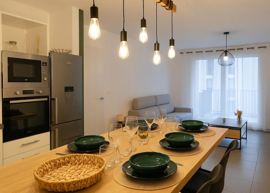 a kitchen with a table with green plates and wine glasses at T3 moderne- Climatisé avec Parking & Terrasse à 5 min de Montpellier in Saint-Jean-de-Védas