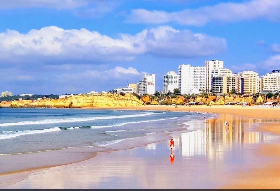 a person walking on the beach with a city in the background at Renaissance sunrises inn in Portimão