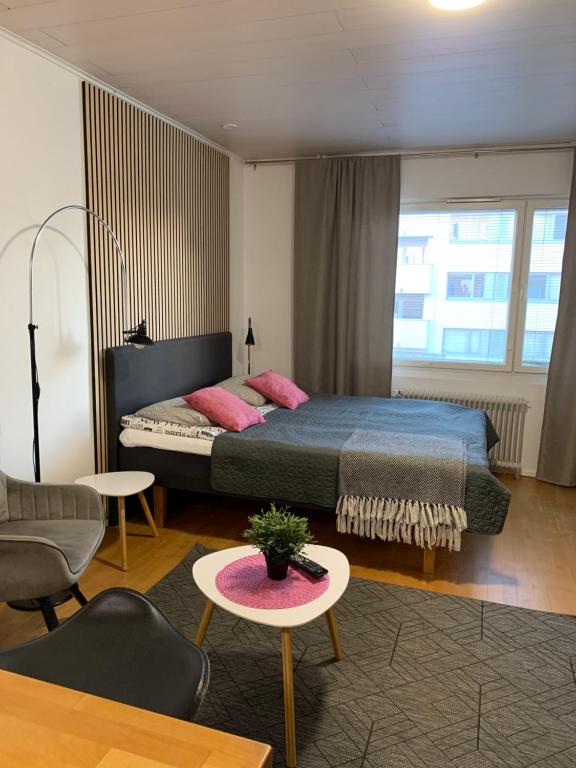 a bedroom with a bed with pink pillows and a table at StarHomes City Studio B16 in Oulu