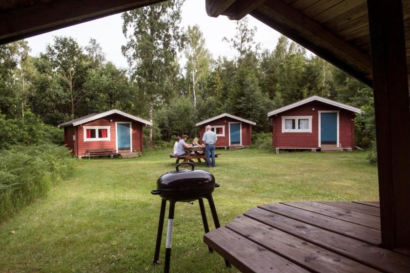 Zwei Personen sitzen an einem Picknicktisch vor einigen Hütten. in der Unterkunft Kloster Gård - Cabins & apartments near Astrid Lindgrens World in Hultsfred