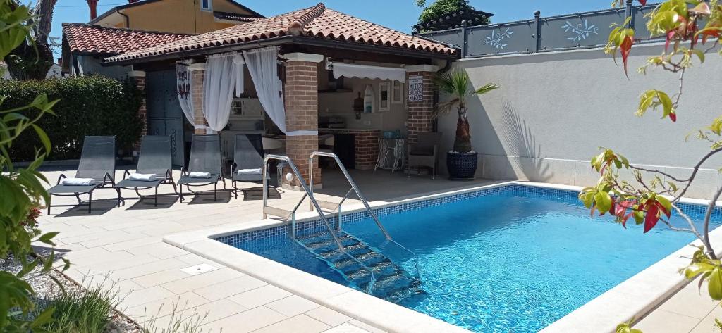 a swimming pool with a gazebo next to a house at Casa Providenca in Kaštelir