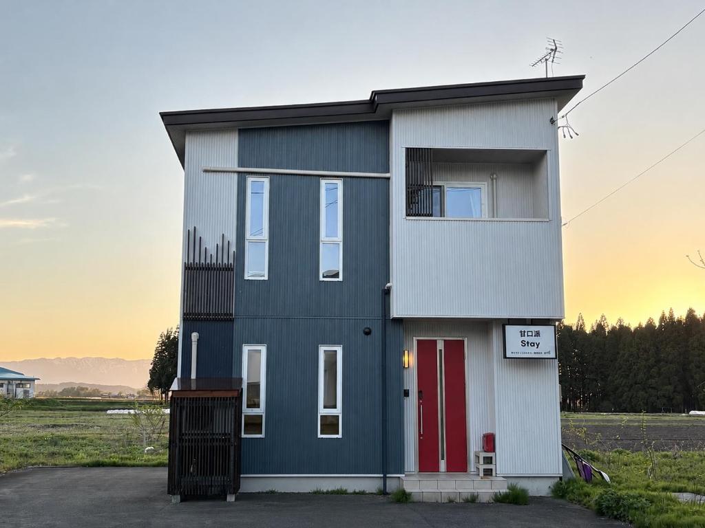 a house with a red door in a field at 甘口派Stay in Tsurumakida