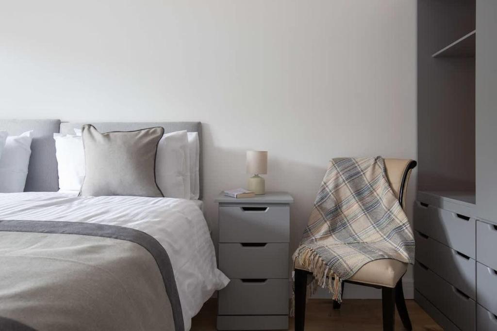 a bedroom with a bed and a chair and a dresser at Cheltenham Cottage in Cirencester
