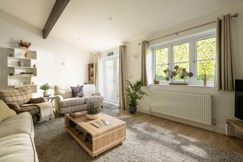 a living room with a couch and a table at Aintree Cottage in Cirencester