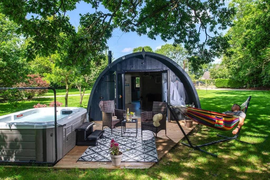 a man laying in a hammock in a tent next to a tub at Squirrels Drey in Hankerton