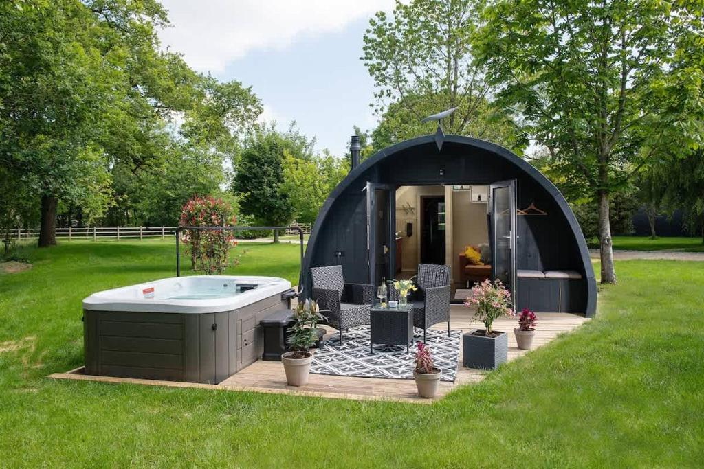 a black dome tent with a hot tub in a yard at Foxes Den in Hankerton