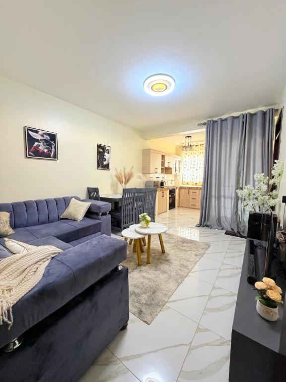 a living room with a blue couch and a table at Plush stays UG in Buwate