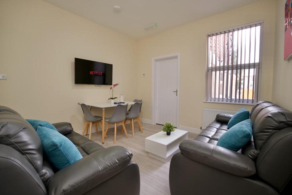 a living room with two leather couches and a table at Hamilton's Rest Serviced Accommodation - Coventry in Coventry