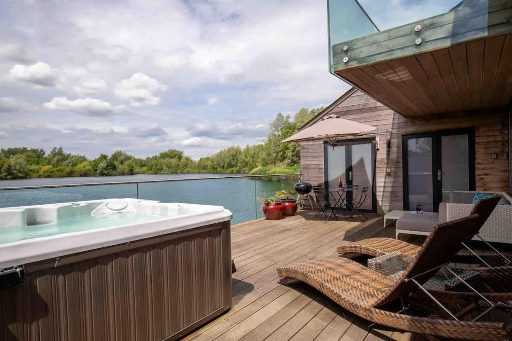 a hot tub on a deck next to the water at Malachite in South Cerney
