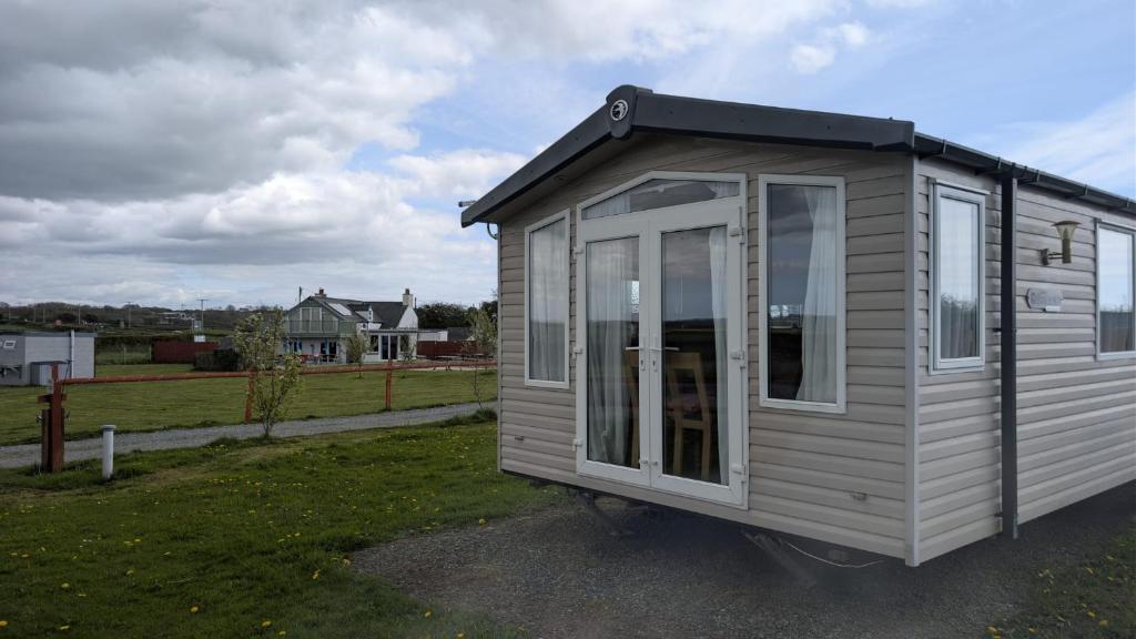 a tiny house is sitting in a yard at The Speculation Inn - 3 Bedroom Static Caravan in Pembroke