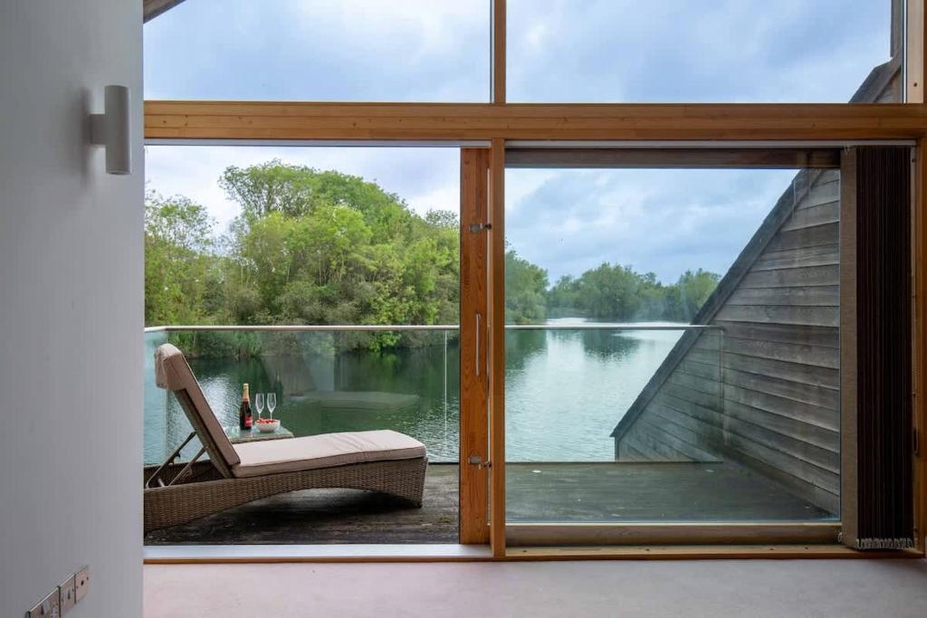 a room with a view of a lake through a window at Goose Landing in South Cerney