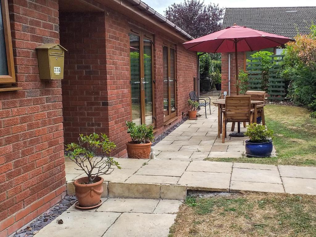 a patio with a table and an umbrella at Little Acorns in Great Malvern