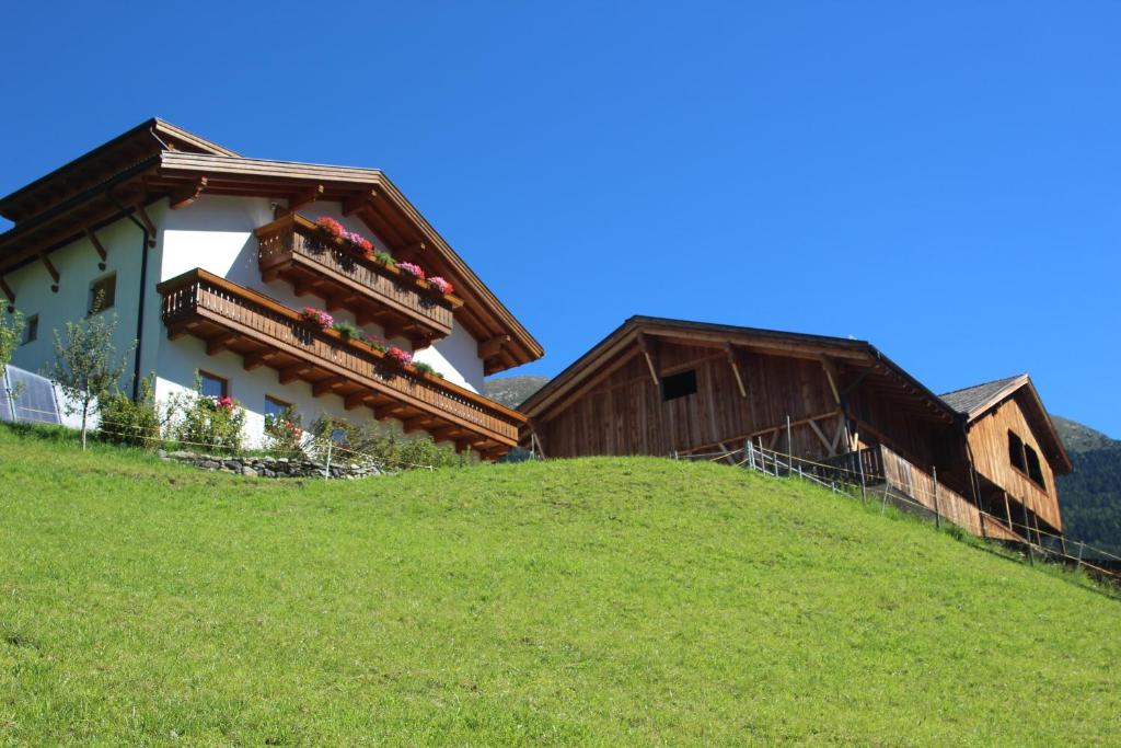 a house on top of a grassy hill at Aussermairhof in Campo Tures