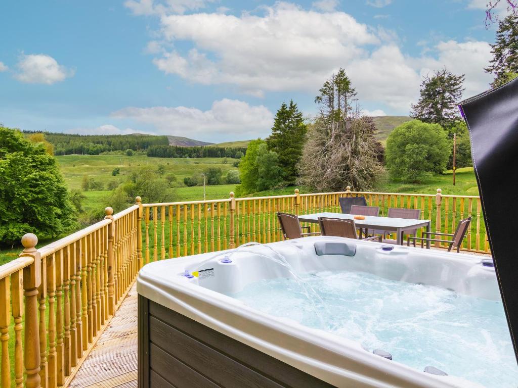 a hot tub on a deck with a table and chairs at Dalnaglar Cottage - Uk30260 in Cray