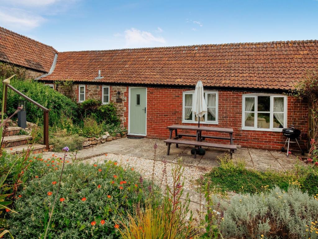 a red brick house with a bench and an umbrella at Carters Cottage - Ukc3947 in Puncknowle