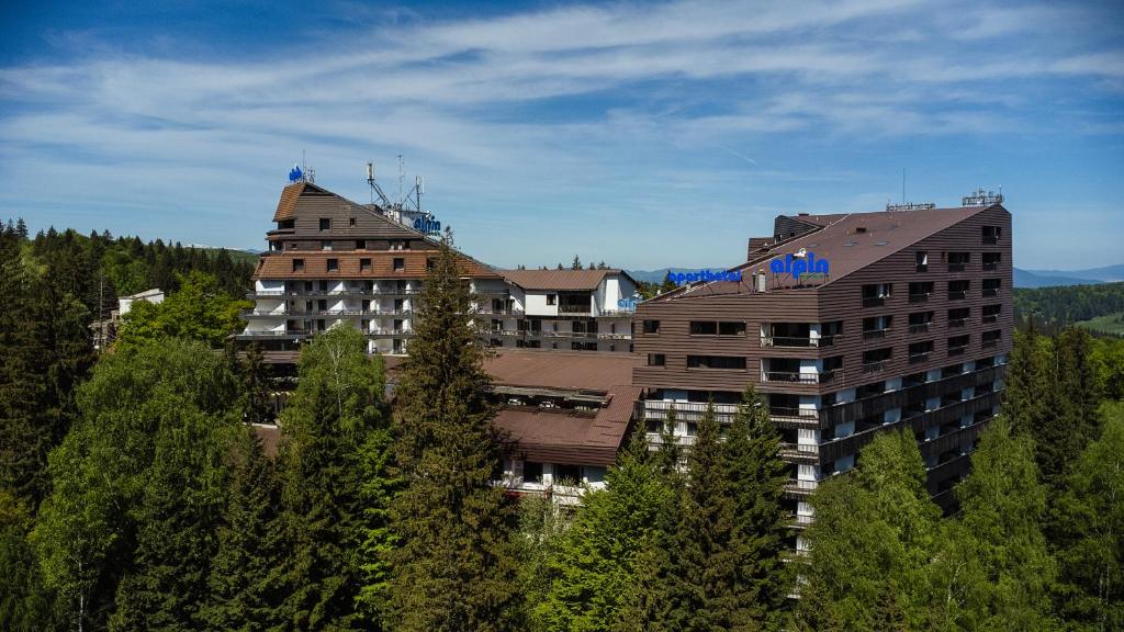 a large building on top of a mountain with trees at Alpin Resort Hotel in Poiana Brasov