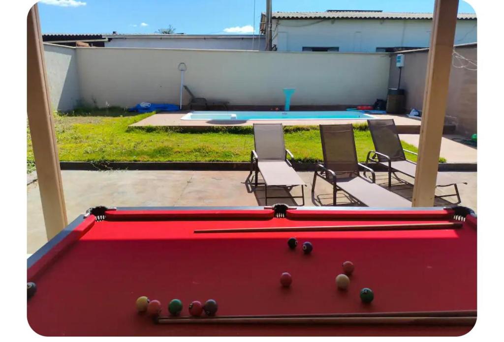 a pool table in a yard with chairs and a swimming pool at Casa gonçalves in Trindade