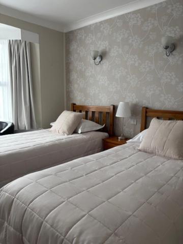 a bedroom with two beds and a window at Canterbury Guest House in Sidmouth