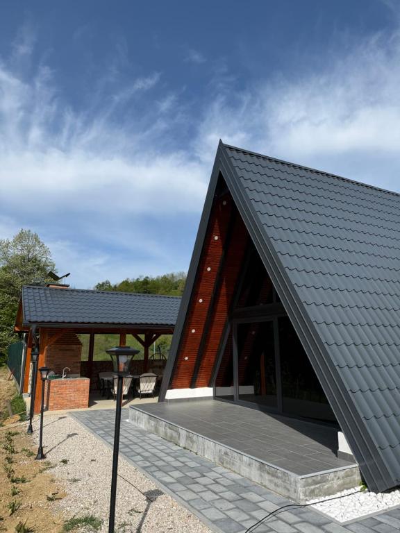 a house with a black roof with a porch at Vila Mirra in Teslić